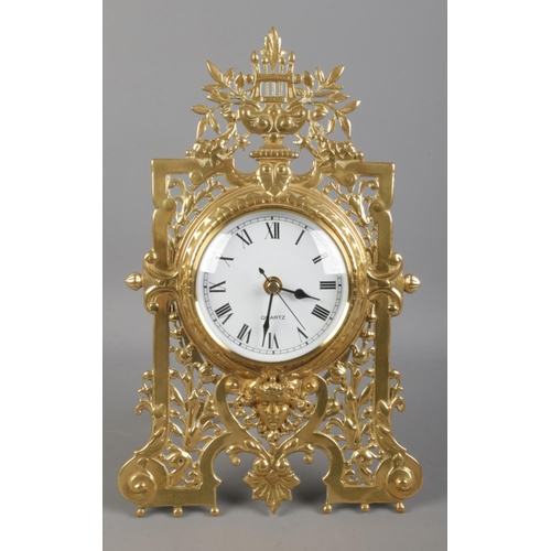 66 - A brass easel desk clock, with pierced scrolled and floral front. Height: 31cm. Fitted with later qu... 