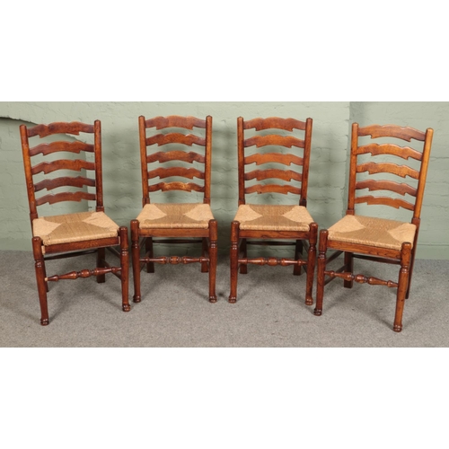 498 - A set of four oak ladder back dining chairs, with rush bases.