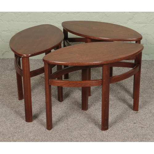 501 - A retro stained teak Nathan Trinity style glass topped coffee table, with three smaller elliptical t... 