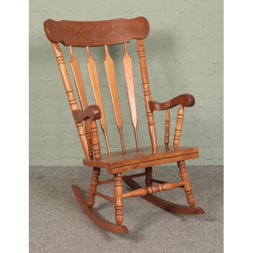 502 - A large pine wingback rocking chair, with turned supports, reeded back and pineapple etched into bac... 