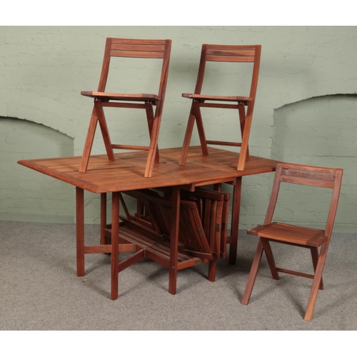 505 - A teak folding garden table, with six folding chairs. From 'The Milan Collection'.