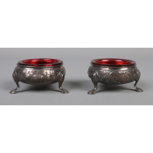 78 - A pair of George III silver salts with red glass liners and raised on three scrolled feet. Assayed L... 