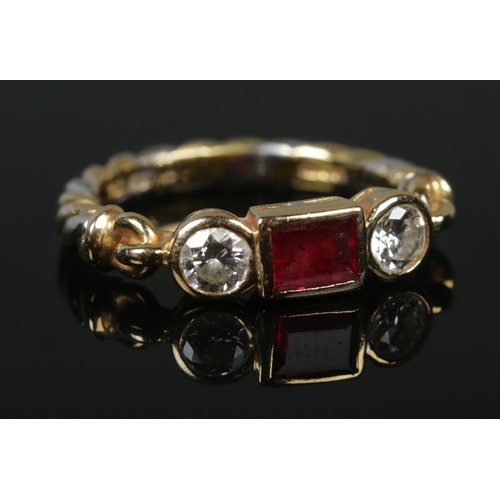 121 - An 18ct yellow and white gold ruby and diamond ring. The central square cut ruby flanked by two bril... 