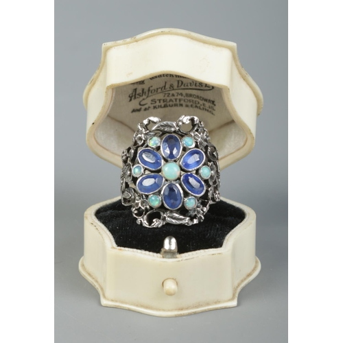 101 - An Arts & Crafts silver ring of floral design, set with sapphire coloured and opal stones. Size P. 6... 