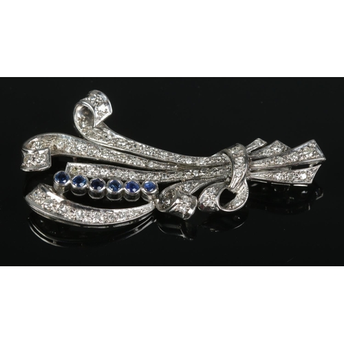 107 - An Art Deco platinum, diamond and sapphire brooch of scroll form. Length 6cm. 9.6g.
