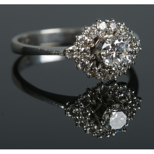 124 - A vintage 18ct white gold and diamond ring. The central stone surrounded by a halo of sixteen smalle... 