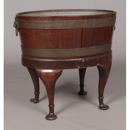 153 - A mahogany wine cooler with twin lion mask handles and raised on four cabriole supports. Height 58cm... 