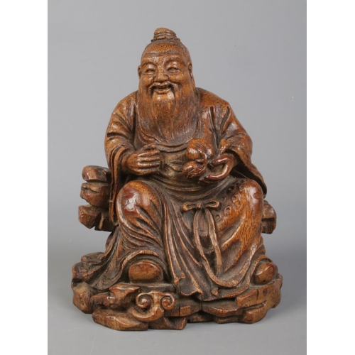36 - A Chinese carved bamboo figure formed as Dongfang Shuo seated in robes and holding a peach of immort... 