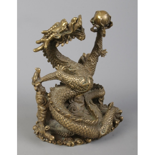 38 - A cast bronze sculpture of a Chinese dragon holding a flaming pearl. Height 18cm.