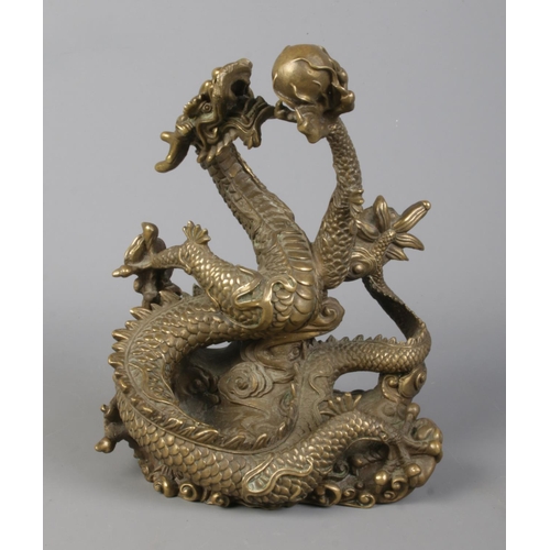 38 - A cast bronze sculpture of a Chinese dragon holding a flaming pearl. Height 18cm.