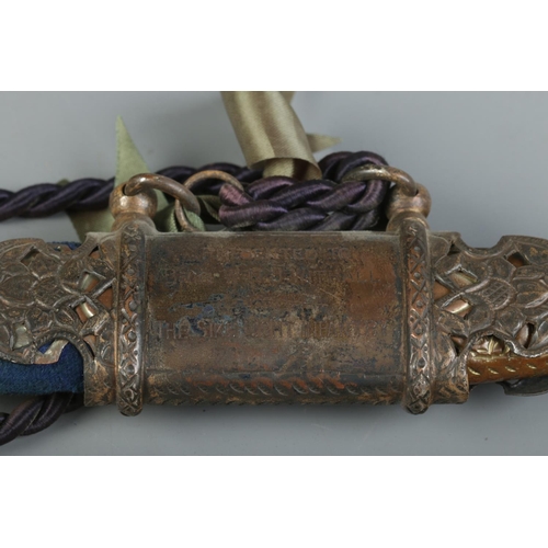 47 - An Indian Tulwar sword with engraved brass handle. The sheath bearing presentation inscription for B... 