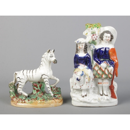 9 - A 19th century Staffordshire figure of a Zebra, along with Staffordshire spill vase modelled as a hu... 