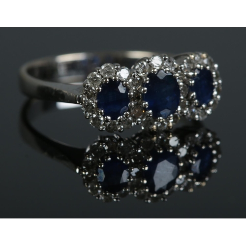 98 - An 18ct white gold, three stone sapphire and diamond ring. Size M. 3.12g.