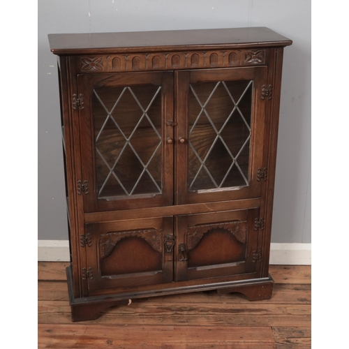 511 - An oak priory style bookcase cabinet with leaded glass doors above a pair of carved panel doors.

Hx... 