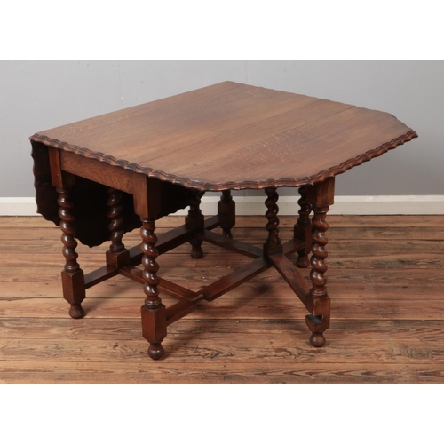 494 - A carved oak barley twist gateleg drop leaf dining table with scalloped edge. (73cm x 106cm x 54cm) ... 