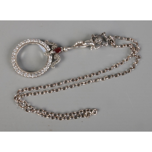 400 - A silver magnifying glass on chain featuring handled formed as a cherub and surrounded by clear ston... 