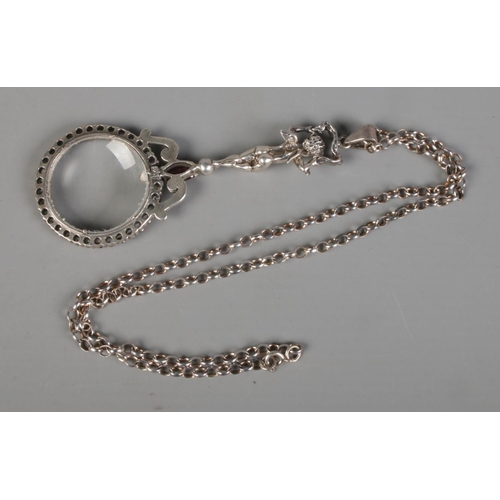 400 - A silver magnifying glass on chain featuring handled formed as a cherub and surrounded by clear ston... 