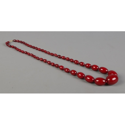 410 - A string of graduated cherry amber bakelite beads on 9ct Gold clasp. Total weight approximately 76g.