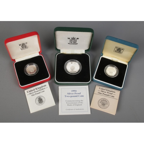 451 - Three cased Royal Mint silver coins. Includes two one pound coins and a 1994 two pound coin.