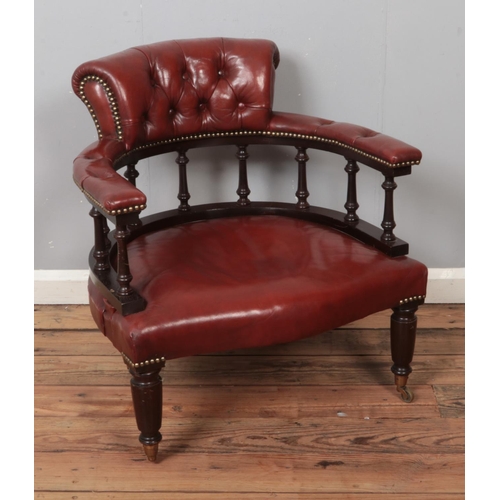 505 - A red leather captains chair with spindle back on turned legs and brass castors