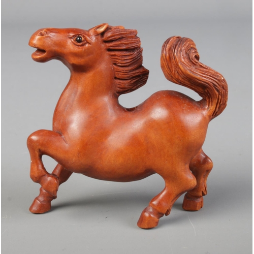 444 - A hand carved hardwood netsuke of a stallion / horse with signature to base.