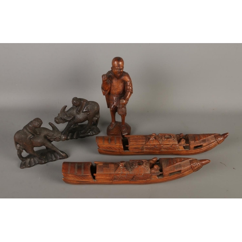 65 - A collection of five carved wooden figures to include pair of boats and figures of children riding b... 