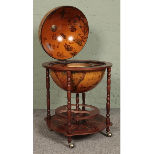 406 - A Globe drinks cabinet, with turned oak supports, hinged top, horoscopic border and rotating base. R... 