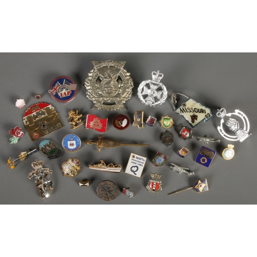 100 - A quantity of badges. Includes military, enamel examples, etc.