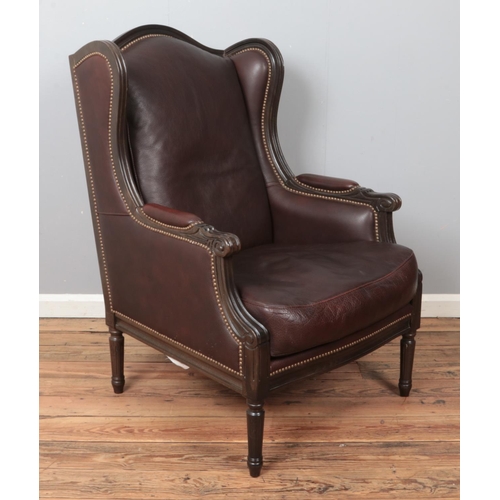 441 - A modern leather wingback armchair, with studded back and wings, padded arms and turned reeded feet.... 