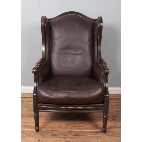 441 - A modern leather wingback armchair, with studded back and wings, padded arms and turned reeded feet.... 