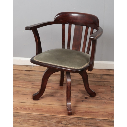 444 - An oak captains swivel chair featuring upholstered seat and slat back support.