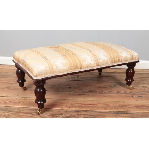 456 - A Victorian style footstool with turned mahogany supports. Height 38cm, Width 94cm, Depth 51cm.