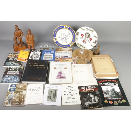 178 - A box of mining collectables and ephemera. Includes wooden figures, flat cap with badges, books, lis... 