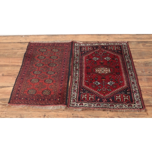 230 - Two small red ground wool rugs featuring fringed edges and floral pattern detail. Approx. length of ... 