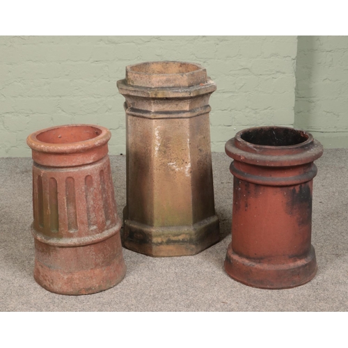 255 - Three terracotta chimney pots. Includes octagonal example and two cylindrical. Tallest 64cm.