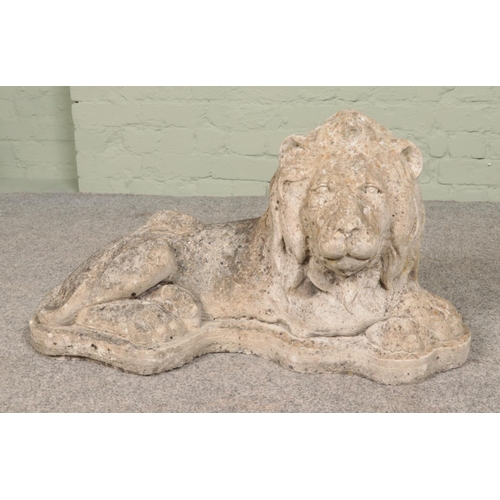 264 - A cast concrete garden statue formed as a recumbent lion. 84cm long.