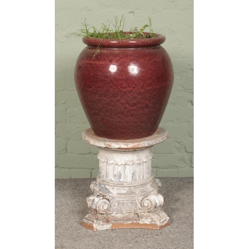 278 - A red glazed plant pot, paired with a small composite 'stone effect' pillar.