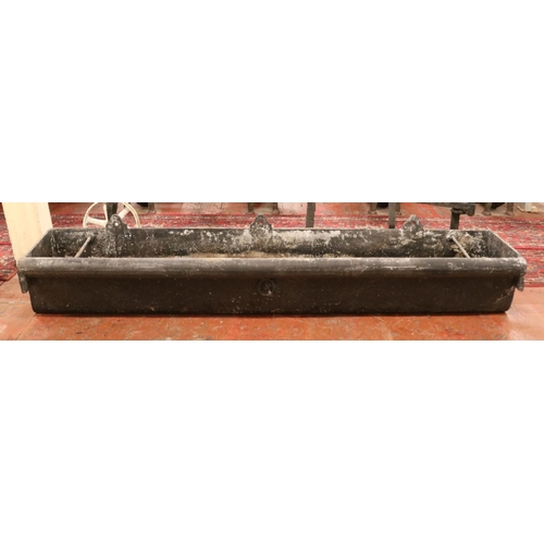 283 - A very large cast iron garden trough, with central tie ring and roll top to one side. Length: 183cm.