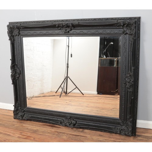 288 - A large moulded composite bevel edged wall mirror. Height: 130cm, Width: 157cm.