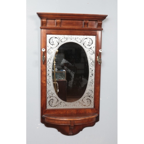 303 - A mahogany framed hall mirror. Having etched glass border, coat hooks and shelf. Length 102cm.