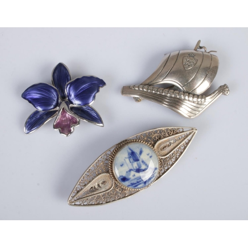 343 - Three silver brooches. Includes enamelled floral example, Danish silver Viking boat, etc.