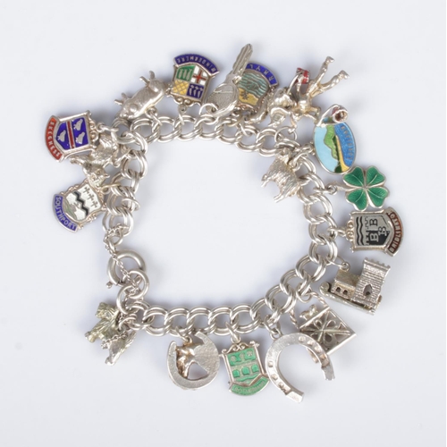 382 - A silver charm bracelet featuring nineteen charms including horseshoe, highland terrier, church, key... 