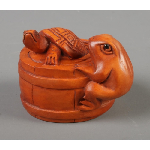 385 - A Japanese carved Netsuke in the form of a turtle and a frog in a barrel.