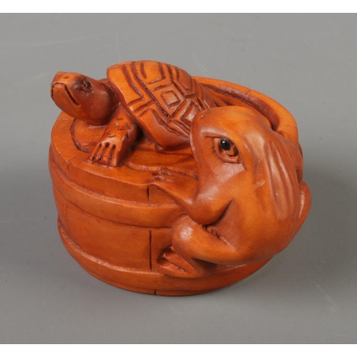 385 - A Japanese carved Netsuke in the form of a turtle and a frog in a barrel.