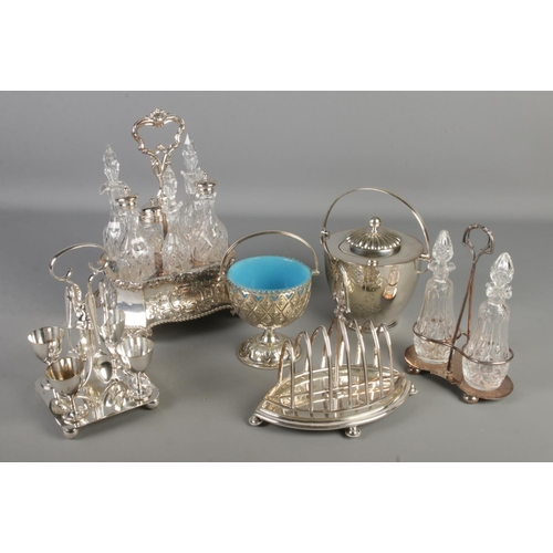 94 - A collection of silver plated items. Includes six bottle cruet set, seven bar toast rack, Mappin & W... 