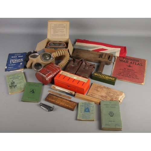 163 - A box of WWII collectables. Includes gas masks, United Kingdom flag, Dominoes, books, etc.