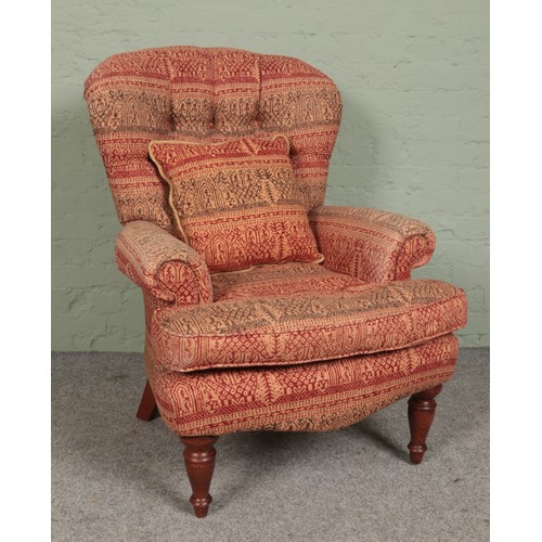 461 - A deep buttoned spoon back armchair, with red and green patterned upholstery and turned front suppor... 