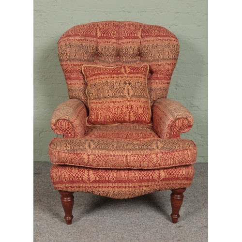 461 - A deep buttoned spoon back armchair, with red and green patterned upholstery and turned front suppor... 