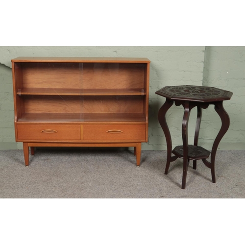 408 - A vintage low teak bookcase, with glass sliding doors and drawer base, together with a carved two ti... 