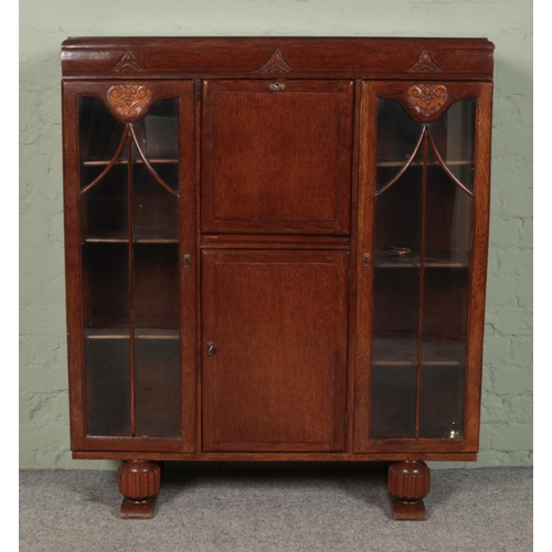 409 - An oak side by side bureau with glazed front, drop down door and carved decoration. Height: 125cm, W... 